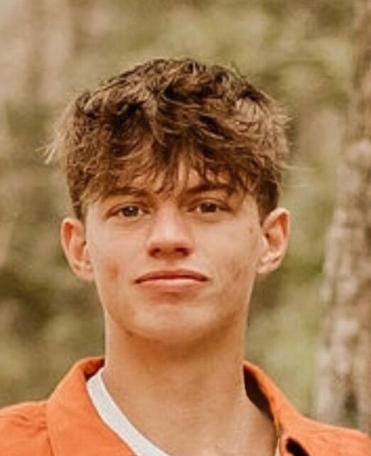 Dane Wheeler smiling at a Jacksonville party company event planning meeting, wearing a suit and standing in an office.