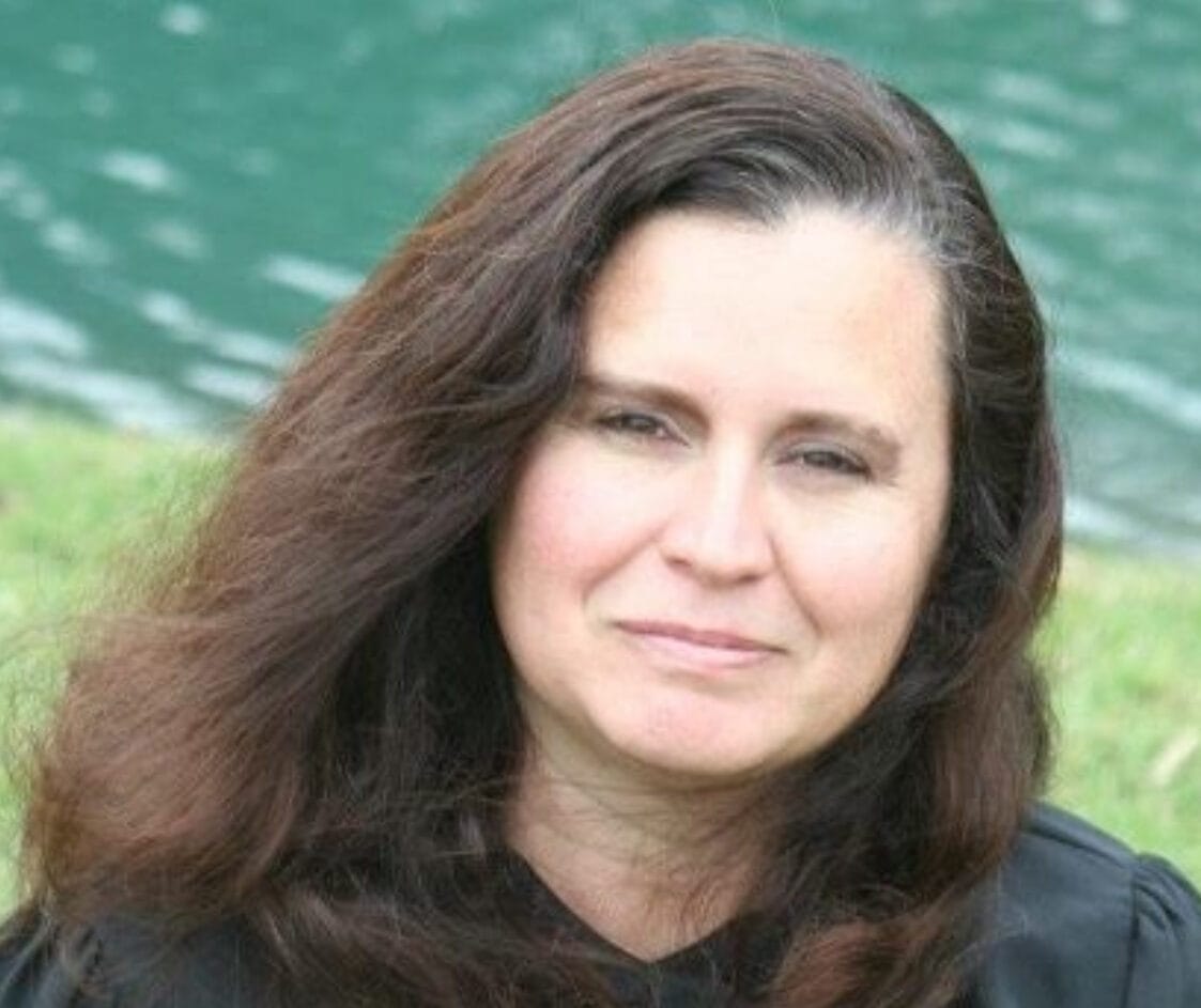 Lisa Wheeler smiling at a Jacksonville party company event planning meeting, wearing a blue blouse and seated at a table.