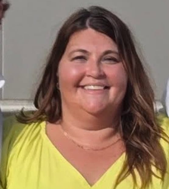 Mandi Jammes smiling at a desk, representing Jacksonville Party Company event planning expertise.