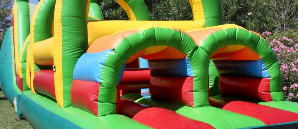 Colorful inflatable bounce house with children playing inside, set up outdoors on a sunny day.