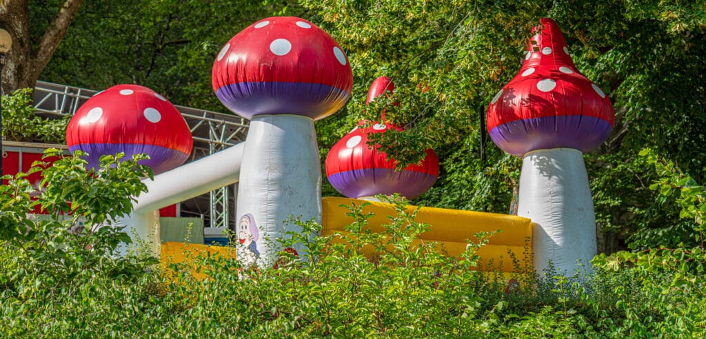 Colorful jumping castle with mushroom-shaped corner towers, set outdoors on a sunny day, suitable for children's parties.