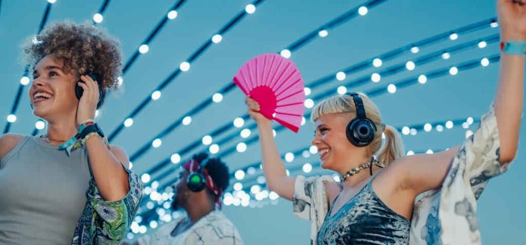 Young people dancing and enjoying music at a vibrant silent party with colorful lights and headphones.