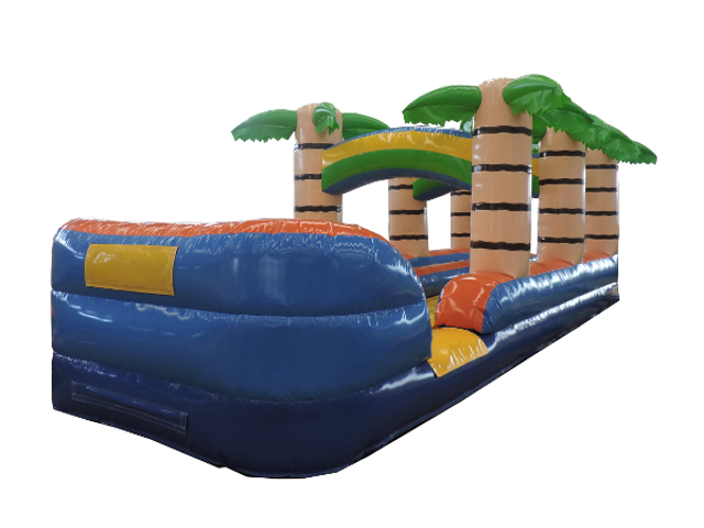 Colorful inflatable slip n slide with palm tree design set up on grass, ready for a fun outdoor event.