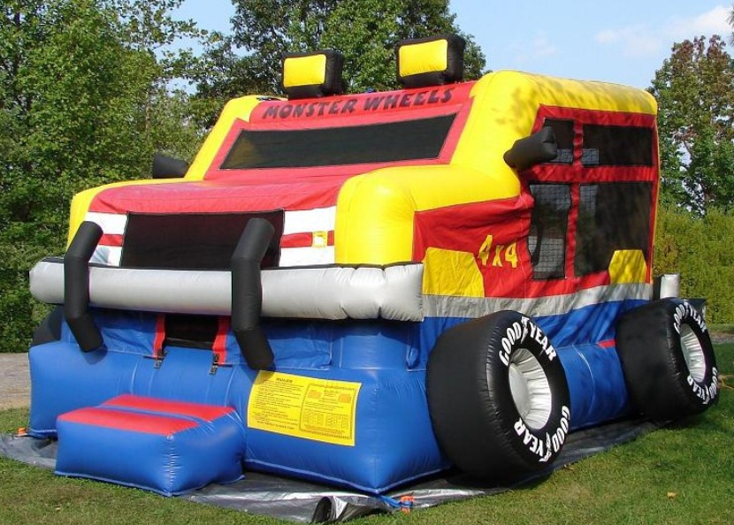 Monster truck bounce house with vibrant colors and large wheels, set up in a grassy area for a party event.