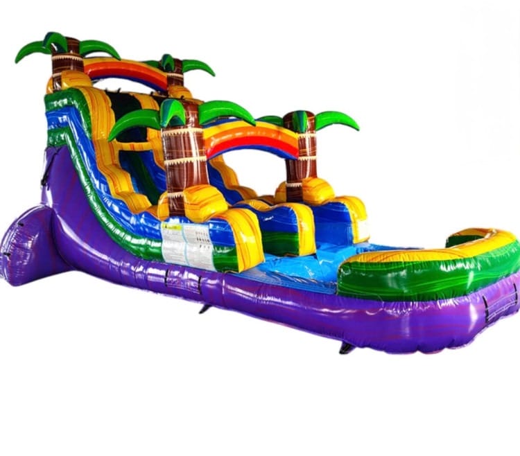 A vibrant inflatable water slide with an Aloha theme, featuring palm trees and a pool at the base, set up in a sunny outdoor